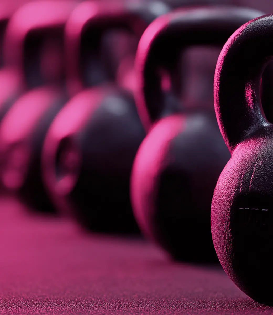 Black kettlebells lined up in a row on a gym floor